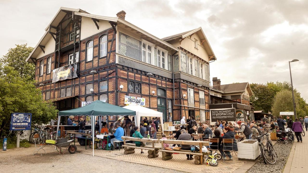 Im Biergarten vor dem ehemaligen Bahnhof in Wuppertal sitzen Menschen, auf einem Transparent an der Backsteinmauer steht "World Disco Soup Day". Im Biergarten vor dem ehemaligen Bahnhof in Wuppertal sitzen Menschen, auf einem Transparent an der Backsteinmauer steht "World Disco Soup Day".