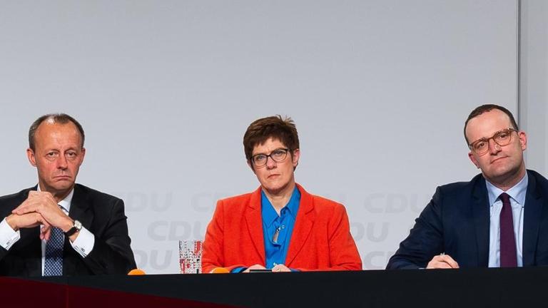 20.11.2018, Rheinland-Pfalz, Idar-Oberstein: Friedrich Merz (l-r), der frühere CDU/CSU-Fraktionschef, Annegret Kramp-Karrenbauer, CDU Generalsekretärin und Jens Spahn (CDU), Gesundheitsminister, sitzen bei der CDU-Regionalkonferenz auf dem Gelände der Messe Idar-Oberstein auf der Bühne. Zur zweiten Vorstellungsrunde der drei aussichtsreichsten Kandidaten für den CDU-Vorsitz sind rund 2000 CDU-Mitgliedern aus Rheinland-Pfalz und aus dem Saarland angereist. Foto: Silas Stein/dpa | Verwendung weltweit