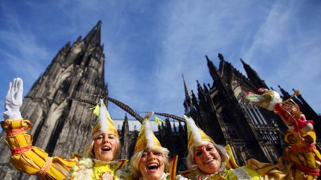 Drei Karnevalistinnen aus Holland in gelben Kostümen winken am 27.02.2014 zur Weiberfastnacht in Köln (Nordrhein-Westfalen) vor dem Kölner Dom.