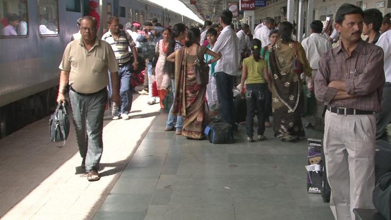 Auf einem Bahnsteig der indischen Hauptstadt Neu-Delhi schieben sich viele Menschen am Gleis entlang. Auf einem Bahnsteig der indischen Hauptstadt Neu-Delhi schieben sich viele Menschen am Gleis entlang.
