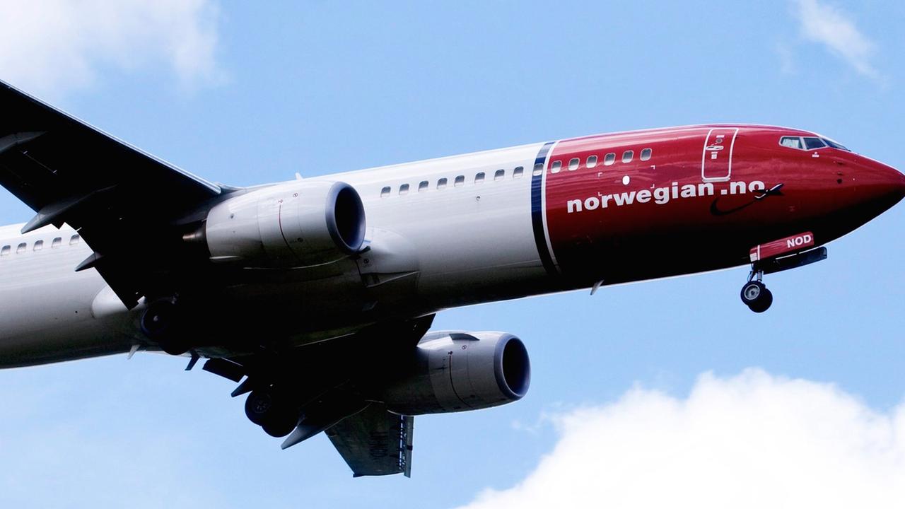 Eine Boeing 737-800 des Billig-Fliegers Norwegian Air Shuttle fliegt vor blauem Himmel