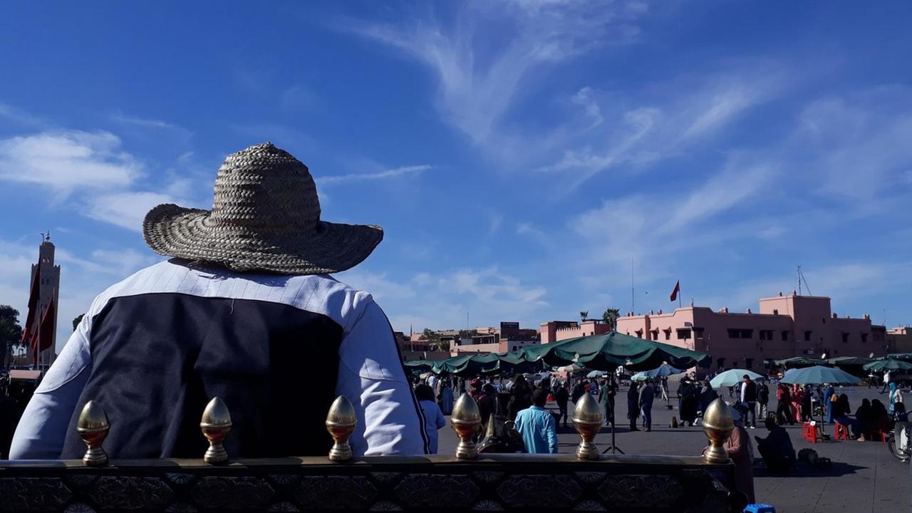 Ein Kutscher von hinten mit Blick auf dem Gauklerplatz und die Hauptmoschee in Marrakesch Ein Kutscher von hinten mit Blick auf dem Gauklerplatz und die Hauptmoschee in Marrakesch