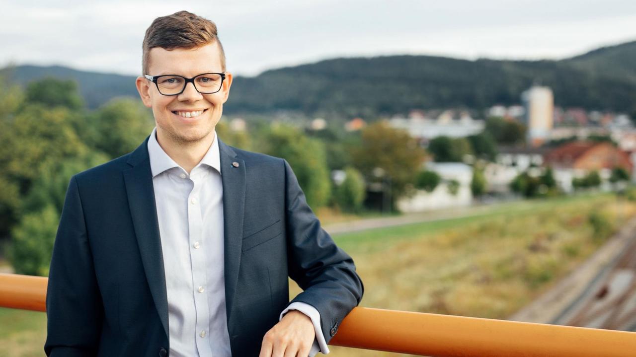 Daniel Schultheiß, Oberbürgermeister von Ilmenau, lehnt an einem Geländer. Im Hintergrund ist Ilmenau zu sehen. Daniel Schultheiß, Oberbürgermeister von Ilmenau, lehnt an einem Geländer. Im Hintergrund ist Ilmenau zu sehen.