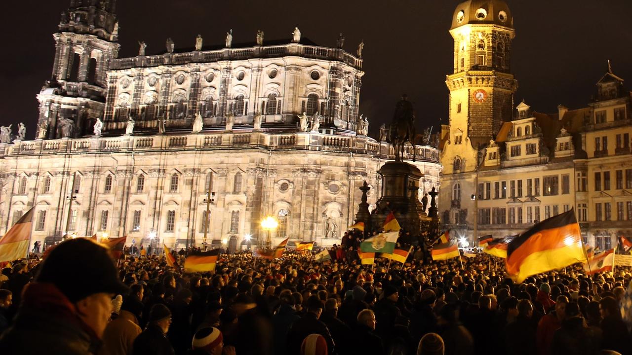 Anhänger des "Pegida"-Bündnisses (Patriotische Europäer gegen die Islamisierung des Abendlandes) demonstrieren in Dresden gegen die angebliche Überfremdung durch Flüchtlinge und schwenken Deutschlandfahnen. Anhänger des "Pegida"-Bündnisses (Patriotische Europäer gegen die Islamisierung des Abendlandes) demonstrieren in Dresden gegen die angebliche Überfremdung durch Flüchtlinge und schwenken Deutschlandfahnen.