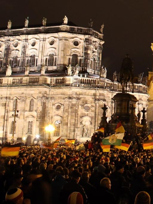 Anhänger des "Pegida"-Bündnisses (Patriotische Europäer gegen die Islamisierung des Abendlandes) demonstrieren in Dresden gegen die angebliche Überfremdung durch Flüchtlinge und schwenken Deutschlandfahnen.