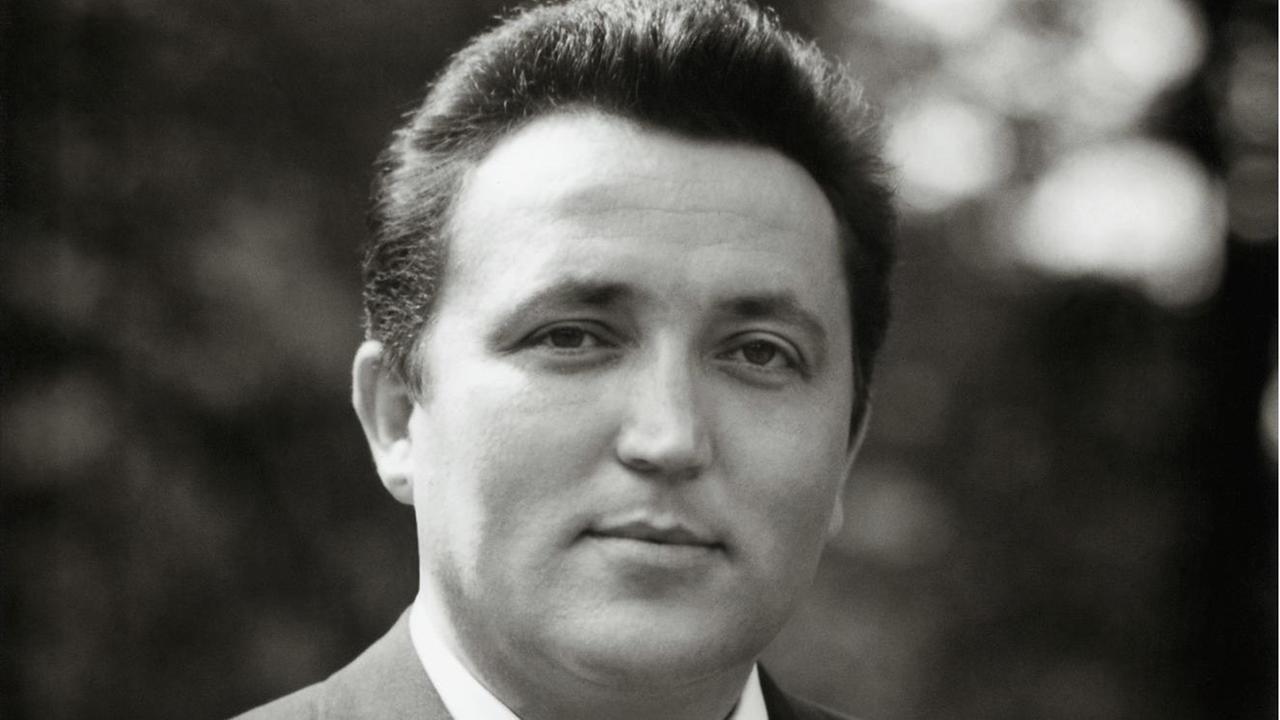 Das Porträtbild eines lächelnden ca. 35-jährigen Mannes mit kurzen Haaren (schwarz-weiß).