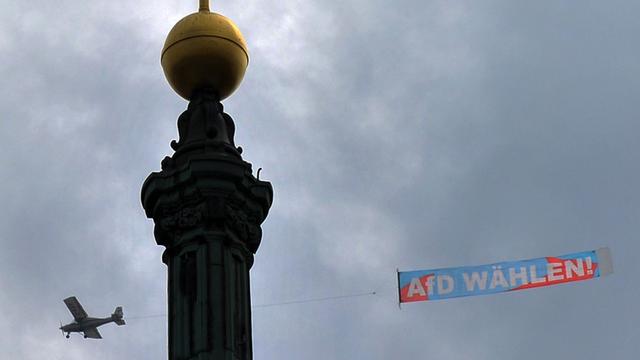 "AfD wählen!" Ein Flugzeug fliegt mit einem Transparent über Dresden, hier an der Spitze der Katholischen Hofkirche vorbei.