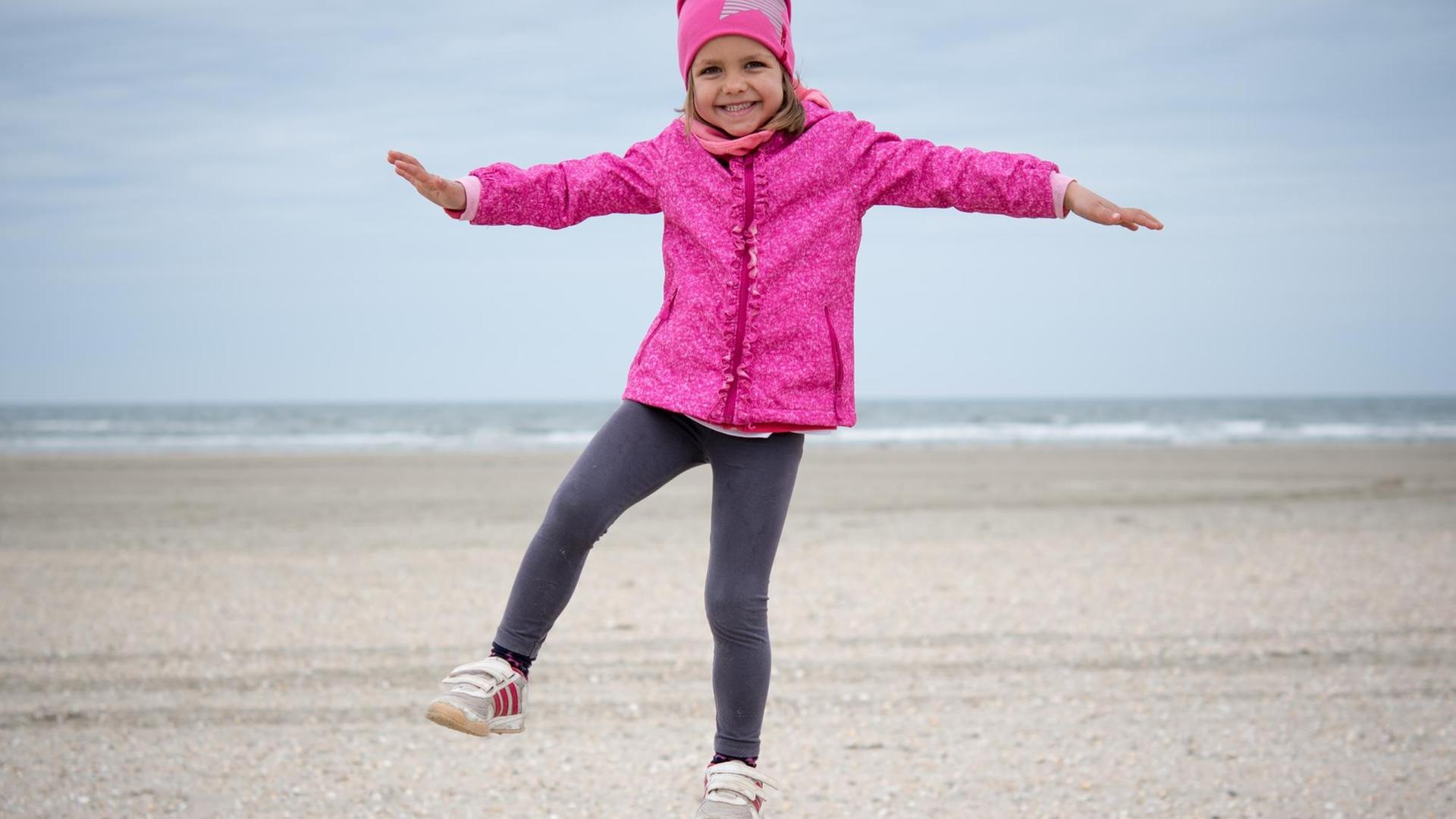 Ein vierjähriges Mädchen beim Balancieren auf einem Holzpfosten am Strand der dänischen Insel Römö. Ein vierjähriges Mädchen beim Balancieren auf einem Holzpfosten am Strand der dänischen Insel Römö.