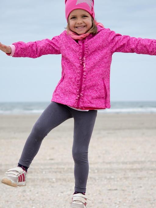 Ein vierjähriges Mädchen beim Balancieren auf einem Holzpfosten am Strand der dänischen Insel Römö.