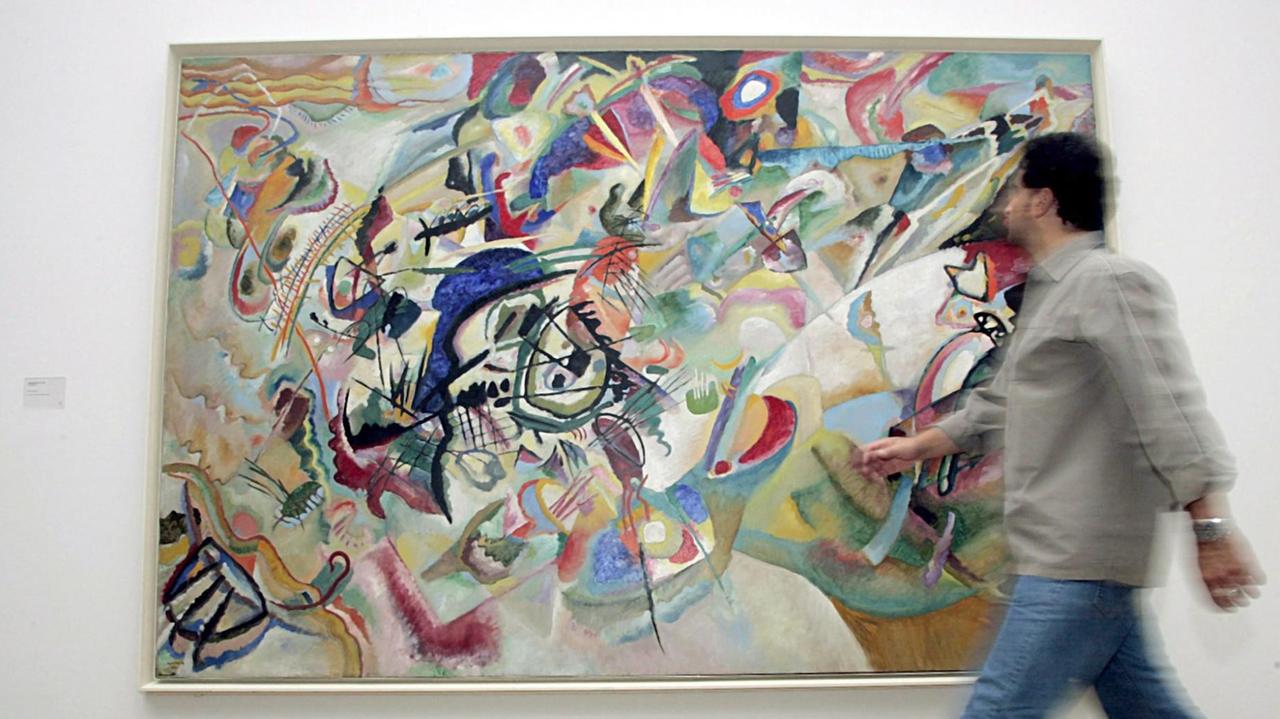 Ein Besucher läuft an einem Gemälde von Kandinsky vorbei, das sich vom Gegenständlichen gelöst hat. 
