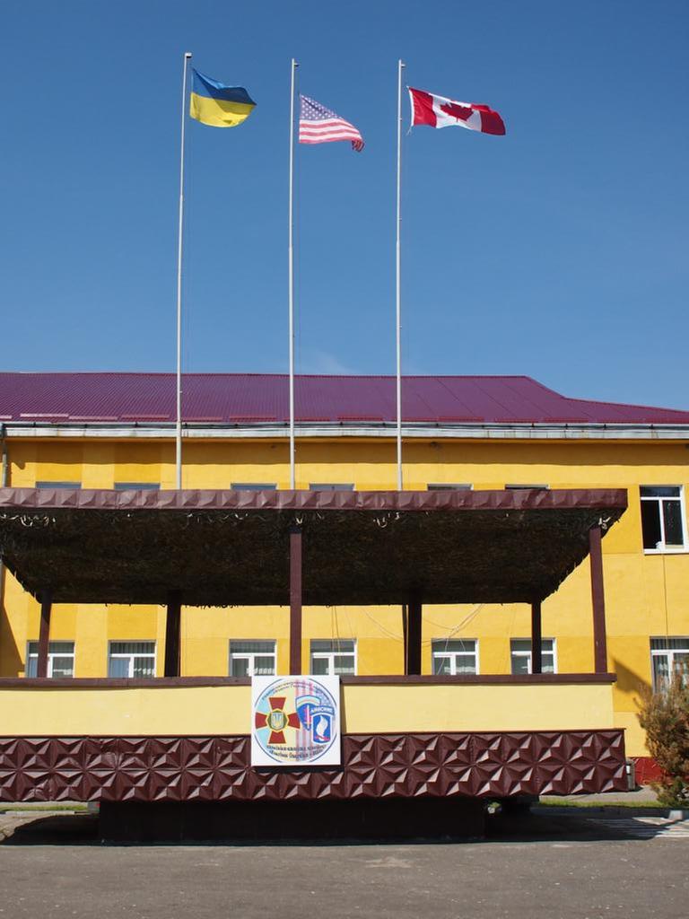 Gelbes Gebäude mit der ukrainischen, amerikanischen und kanadischen Flagge. Gelbes Gebäude mit der ukrainischen, amerikanischen und kanadischen Flagge.