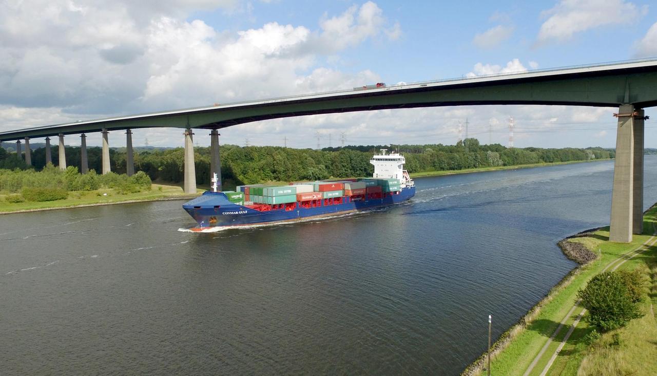 Ein Containerschiff fährt am 03.09.2015 auf dem Nord-Ostsee-Kanal in Höhe der Rader Hochbrücke der Autobahn 7 bei Rendsburg (Schleswig-Holstein). Foto: Carsten Rehder | Verwendung weltweit Ein Containerschiff fährt am 03.09.2015 auf dem Nord-Ostsee-Kanal in Höhe der Rader Hochbrücke der Autobahn 7 bei Rendsburg (Schleswig-Holstein). Foto: Carsten Rehder | Verwendung weltweit