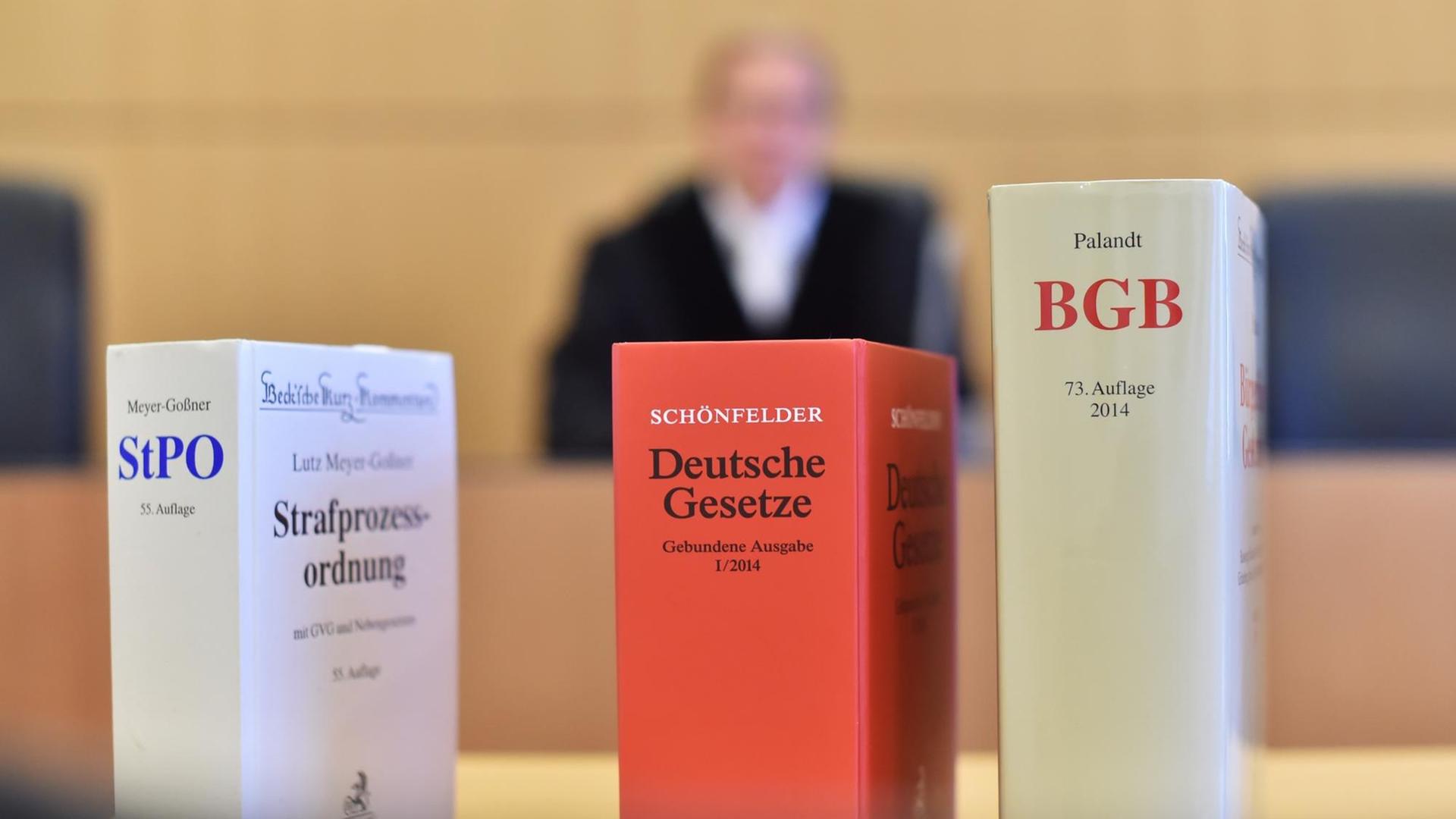  An der Richterbank eines Sitzungssaals beim Oberlandesgericht (OLG) Karlsruhe (Baden-Württemberg) sitzt ein Richter mit Richterrobe, davor stehen Gesetzesbücher