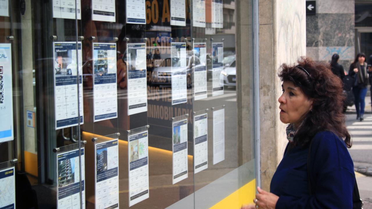 Eine Frau vor dem Fenster eines Maklergeschäfts mit Wohnungsaushängen in Buenos Aires Eine Frau vor dem Fenster eines Maklergeschäfts mit Wohnungsaushängen in Buenos Aires