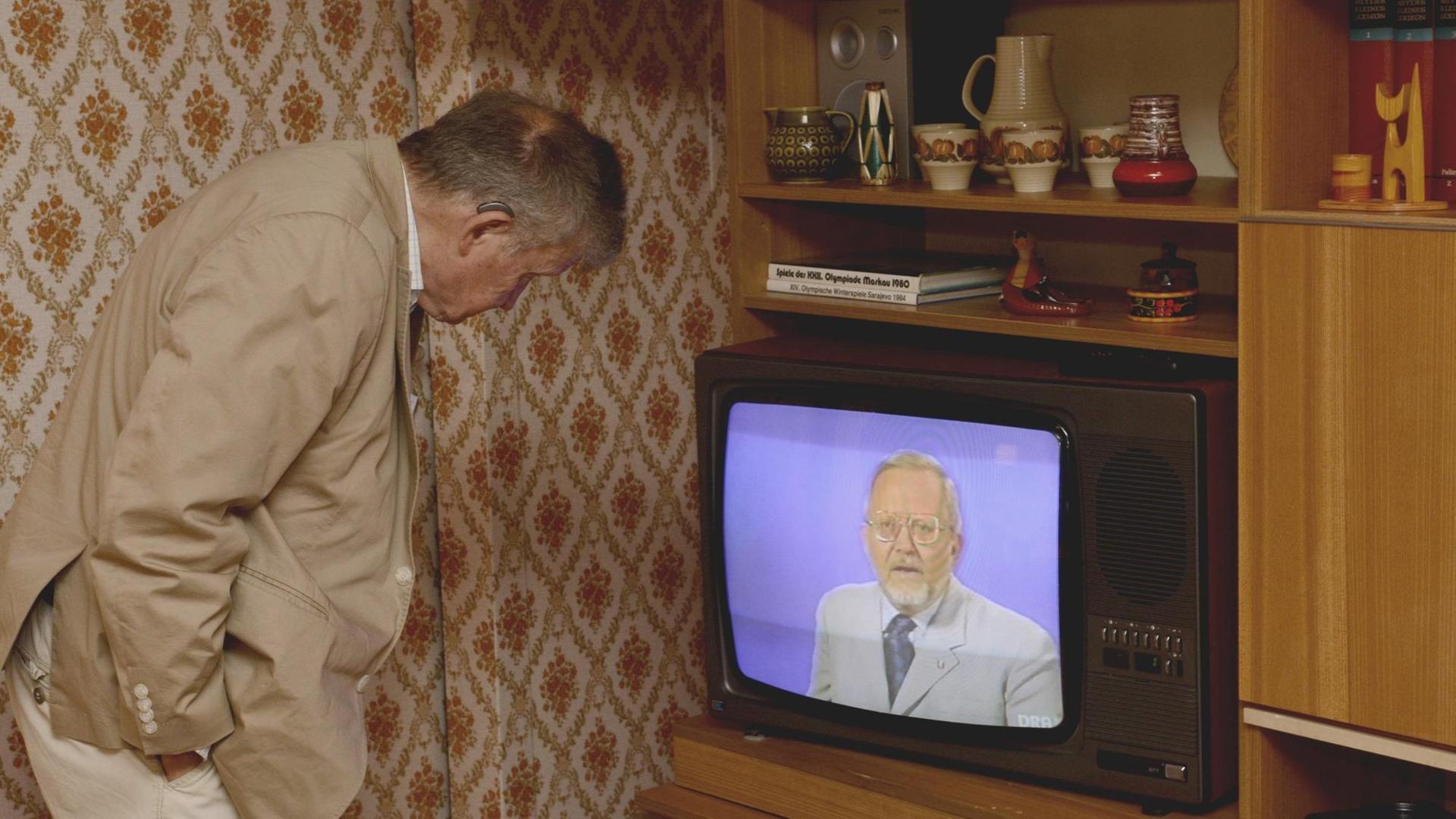 Ein Besucher des DDR-Museums blickt in einen RFT-Fernseher auf dem Eduard Schnitzler zu sehen ist. Dieser steht in einer DDR-typischen Schrankwand in Plattenbauwohnung des Typs WBS 70. Ein Besucher des DDR-Museums blickt in einen RFT-Fernseher auf dem Eduard Schnitzler zu sehen ist. Dieser steht in einer DDR-typischen Schrankwand in Plattenbauwohnung des Typs WBS 70.