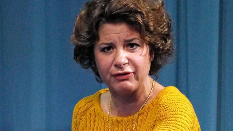 Schauspielerin Anita Vulesica steht im Stück "Yellow Line" am Deutschen Theater Berlin in einem gelben Pullover und weißen Hosen auf der Bühne und streckt den linken Arm nach vorn Schauspielerin Anita Vulesica steht im Stück "Yellow Line" am Deutschen Theater Berlin in einem gelben Pullover und weißen Hosen auf der Bühne und streckt den linken Arm nach vorn