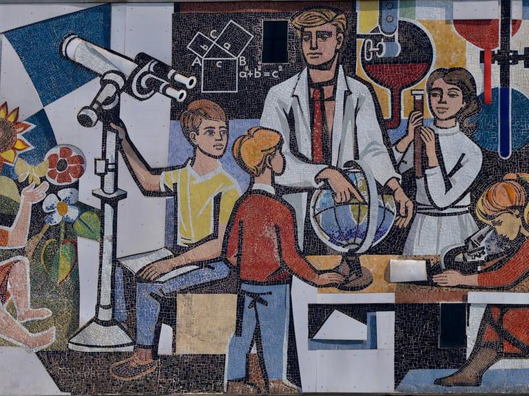 Ein Lehrer im Kreis seiner mit Globus, Mikroskop und Teleskop forschenden Schüler - Mosaik von Walter Womacka an der Fassade des "Haus des Lehrers" am Alexanderplatz in Berlin