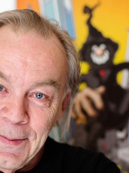 Der Comiczeichner Gerhard Seyfried steht vor einem Plakat seiner Figur _Zwille" in seiner Wohnung in Berlin-Schöneberg.
