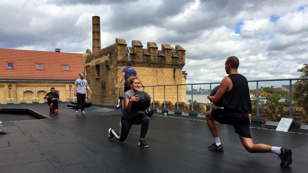 Schufften auf dem Dach - Teilnehmer beim Crossfit Training in Berlin. Schufften auf dem Dach - Teilnehmer beim Crossfit Training in Berlin.