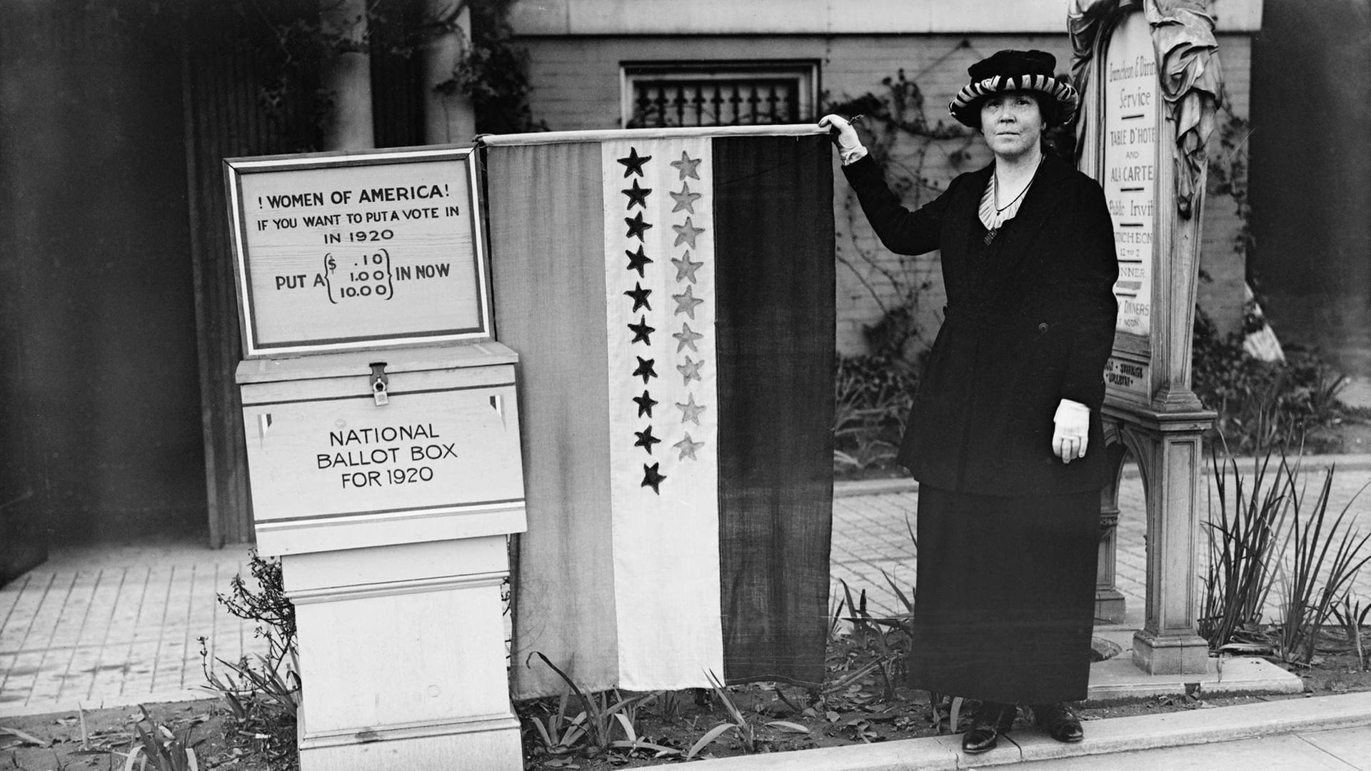 Suffragetten Protest in den USA (04.02.1916). Eine Frau sammelt Geld für die Frauenwahlrechtsbewegung. Sie steht vor eine Kiste mit der Aufschrift: "Women of America! If you want to put a vote in in 1920 put a (.10, 1.00, 10.00) in Now, National Ballot Bo