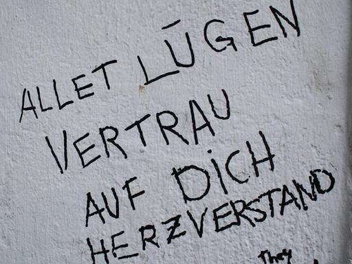 Auf einer Wand steht mit Filzschrift geschrieben: "Allet Lügen. Vertrau auf dich, Herzverstand"