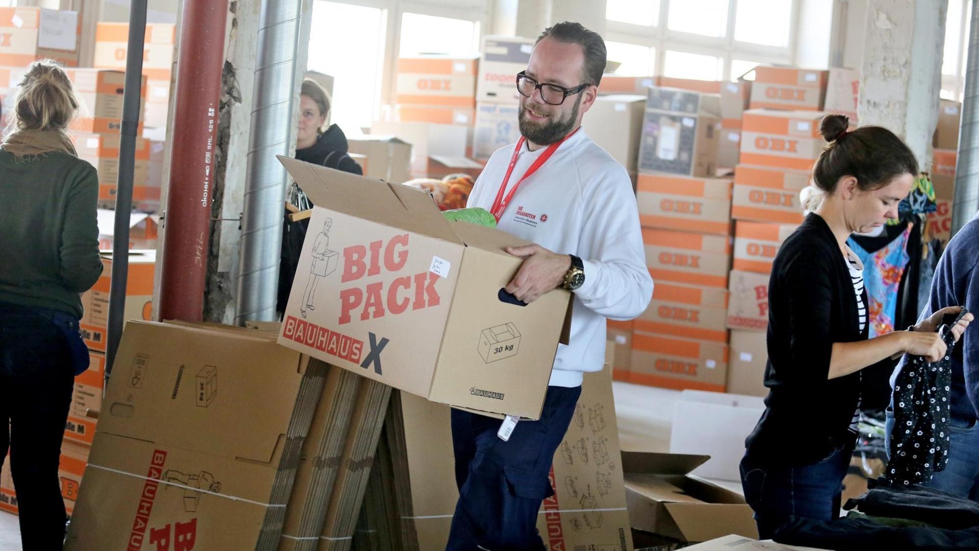 Ein Helfer der Johanniter ordnet Spenden für Flüchtlinge in Leipzig.