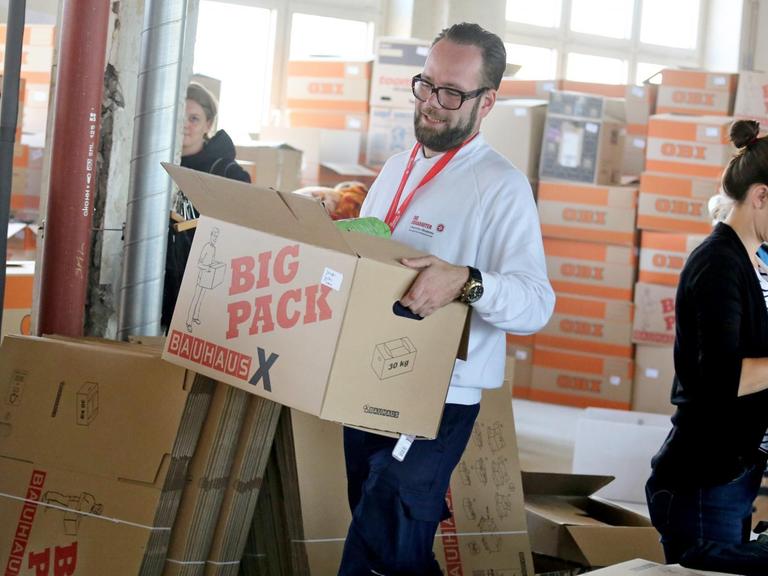 Ein Helfer der Johanniter ordnet Spenden für Flüchtlinge in Leipzig.