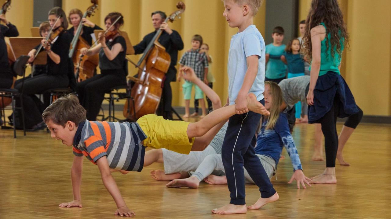 Kinder turnen vor Musikern mit Instrumenten
