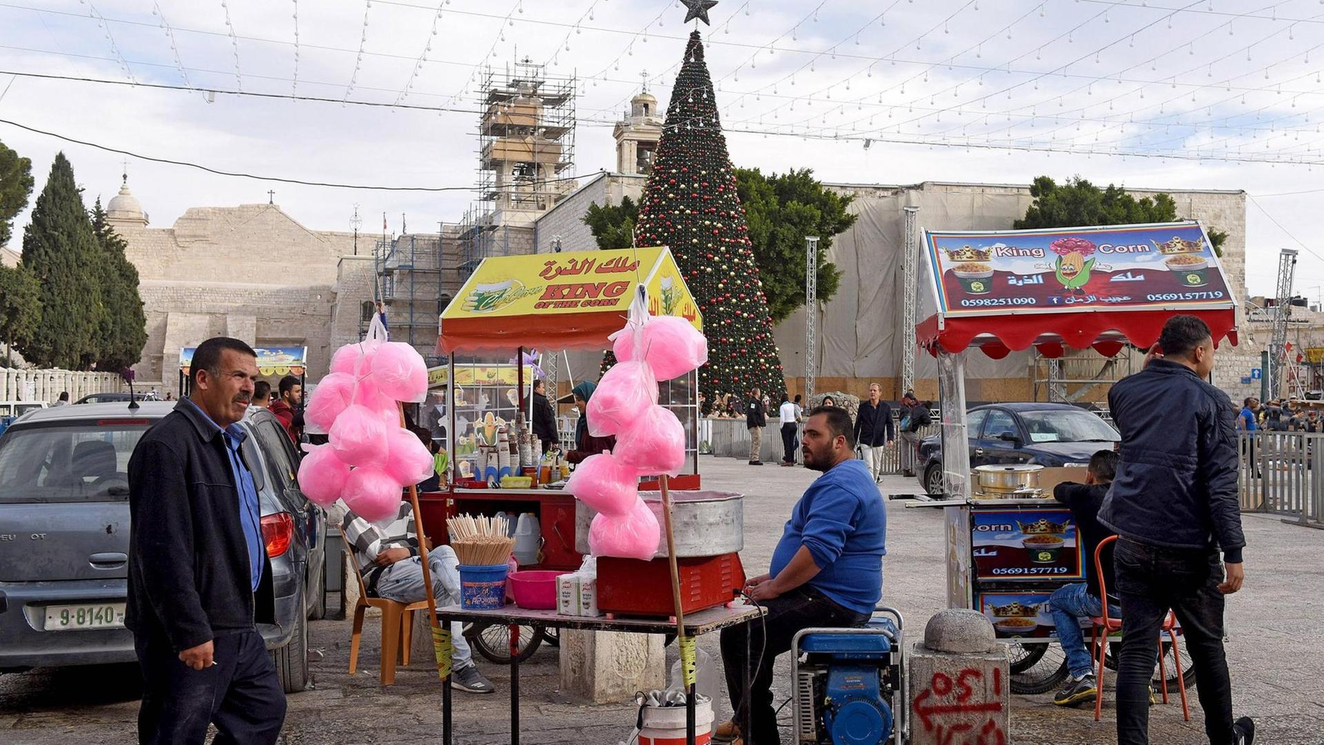 Palästinensische Händler warten mit ihren Imbissständen am 12.12.2017 auf dem Manger-Platz in Bethlehem, Westjordanland, auf Kundschaft (im Hintergrund die Geburtskirche und der traditionelle Weihnachtsbaum).
