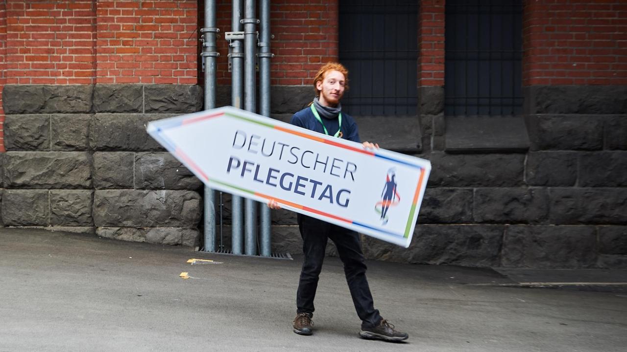 Ein Mann hält in Berlin ein Schild mit der Aufschrift "Deutscher Pflegetag" in den Händen. Ein Mann hält in Berlin ein Schild mit der Aufschrift "Deutscher Pflegetag" in den Händen.