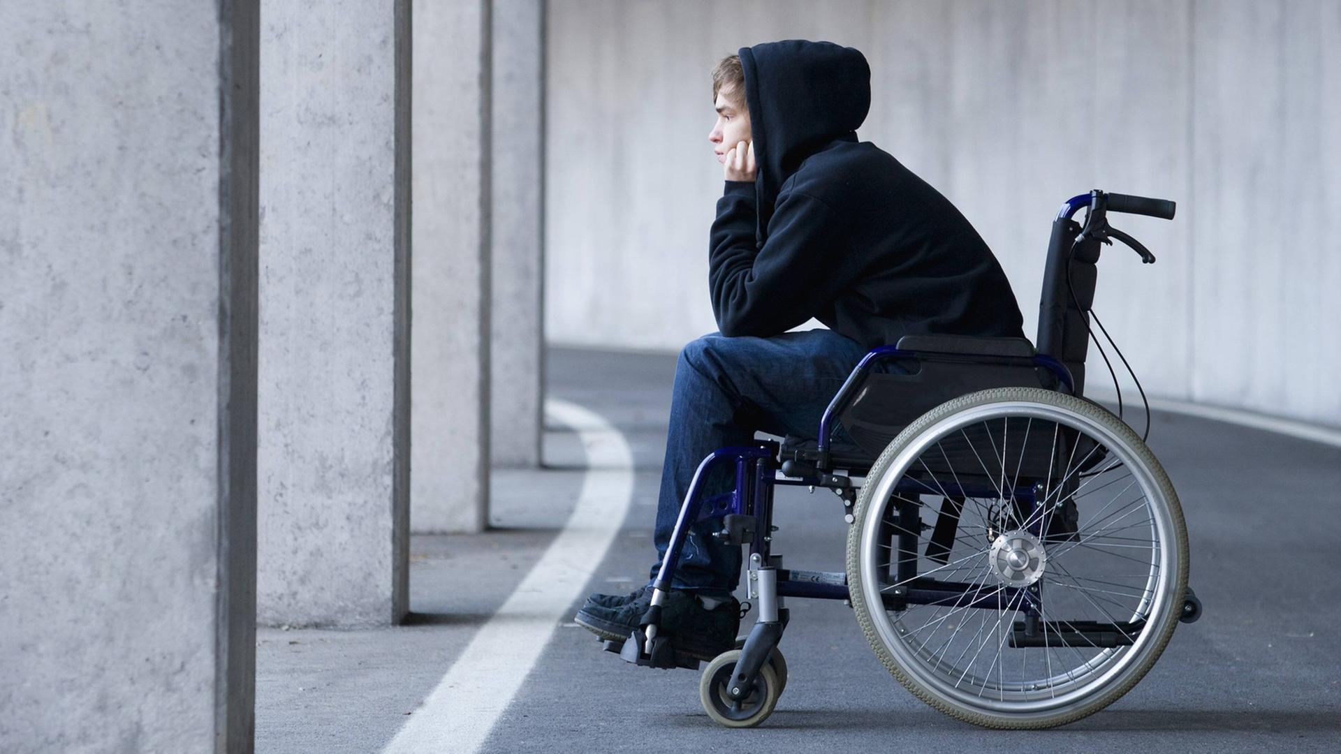 Ein junger Mann sitzt in einem Rollstuhl. Ein junger Mann sitzt in einem Rollstuhl.