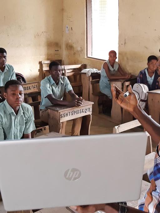 Der Lehrer Earnest Adomensa zeigt den Schülerinnen und Schülern das Microsoft Startmenü auf seidem privaten Laptop.