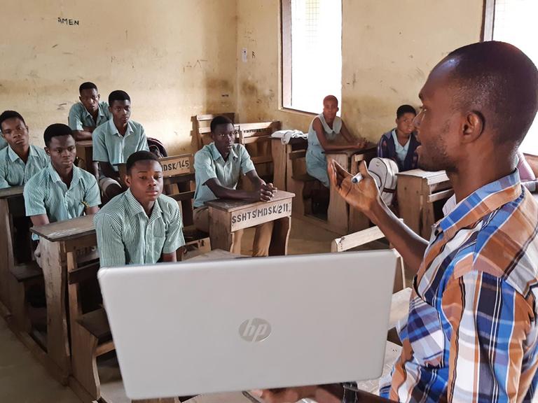 Der Lehrer Earnest Adomensa zeigt den Schülerinnen und Schülern das Microsoft Startmenü auf seidem privaten Laptop.