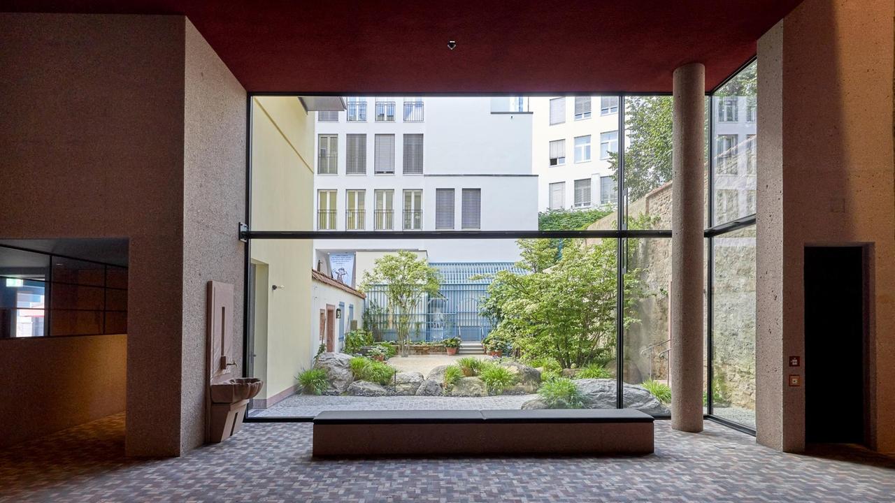 Hinter einer Panorama-Fensterscheibe ist ein Garten zu sehen. Hinter einer Panorama-Fensterscheibe ist ein Garten zu sehen.