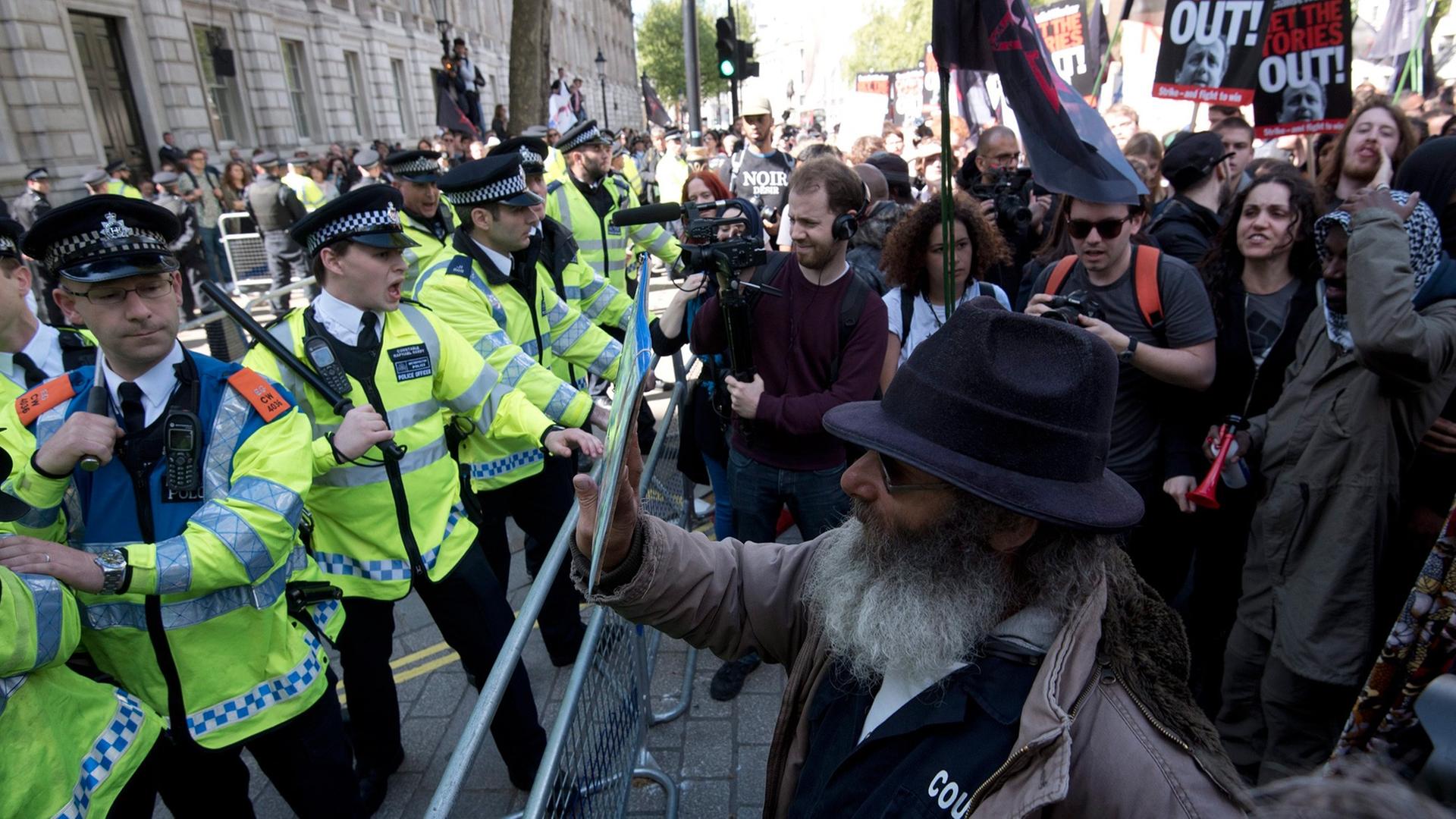 Eine Polizeiabsperrung gegen Demonstranten, die gegen die neue Regierung und deren Sparpolitik protestieren, in der Downing Street in London. Eine Polizeiabsperrung gegen Demonstranten, die gegen die neue Regierung und deren Sparpolitik protestieren, in der Downing Street in London.