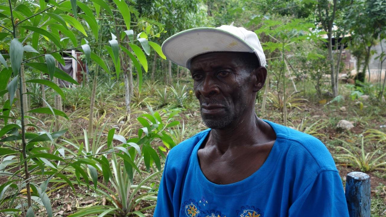 Bauer Silio Cassayoll ist zuversichtlich, auch junge Leute für die klimaangepasste Landwirtschaft gewinnen zu können. Der Haitianer trägt ein blaues T-Shirt und sitzt in einem der Waldgärten.
