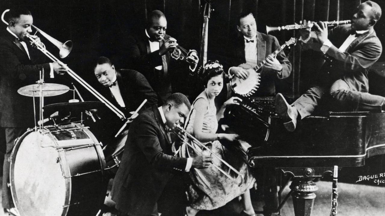 Lillian Harding Armstrong umringt von Jazzmusikern, darunter Louis Armstrong.