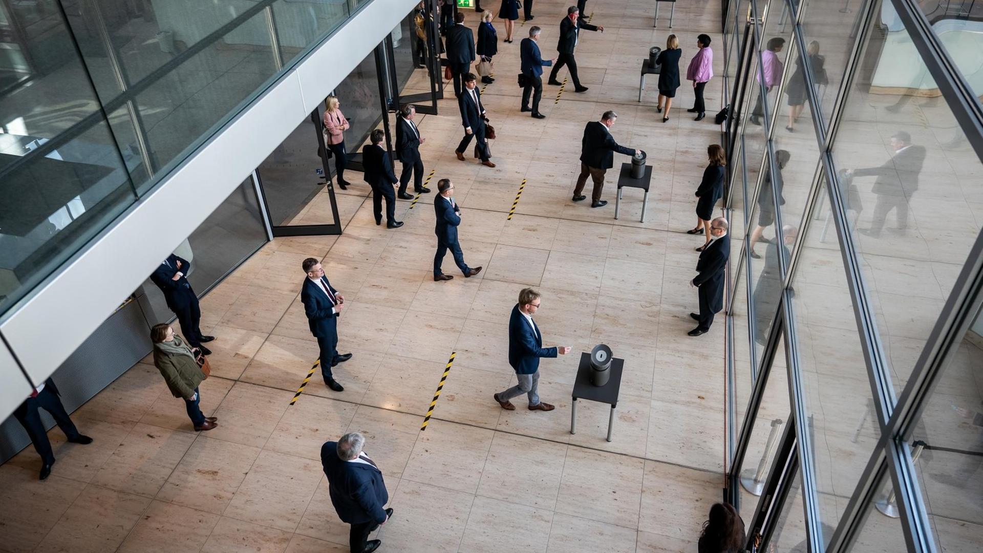 Das Foto zeigt eine Stimmenabgabe im Bundestag mit mehreren aufgestellten Wahlurnen. Auf dem Boden davor befinden sich Striche, damit die Abgeordneten wegen Corona einen Sicherheitsabstand einhalten. Das Foto zeigt eine Stimmenabgabe im Bundestag mit mehreren aufgestellten Wahlurnen. Auf dem Boden davor befinden sich Striche, damit die Abgeordneten wegen Corona einen Sicherheitsabstand einhalten.