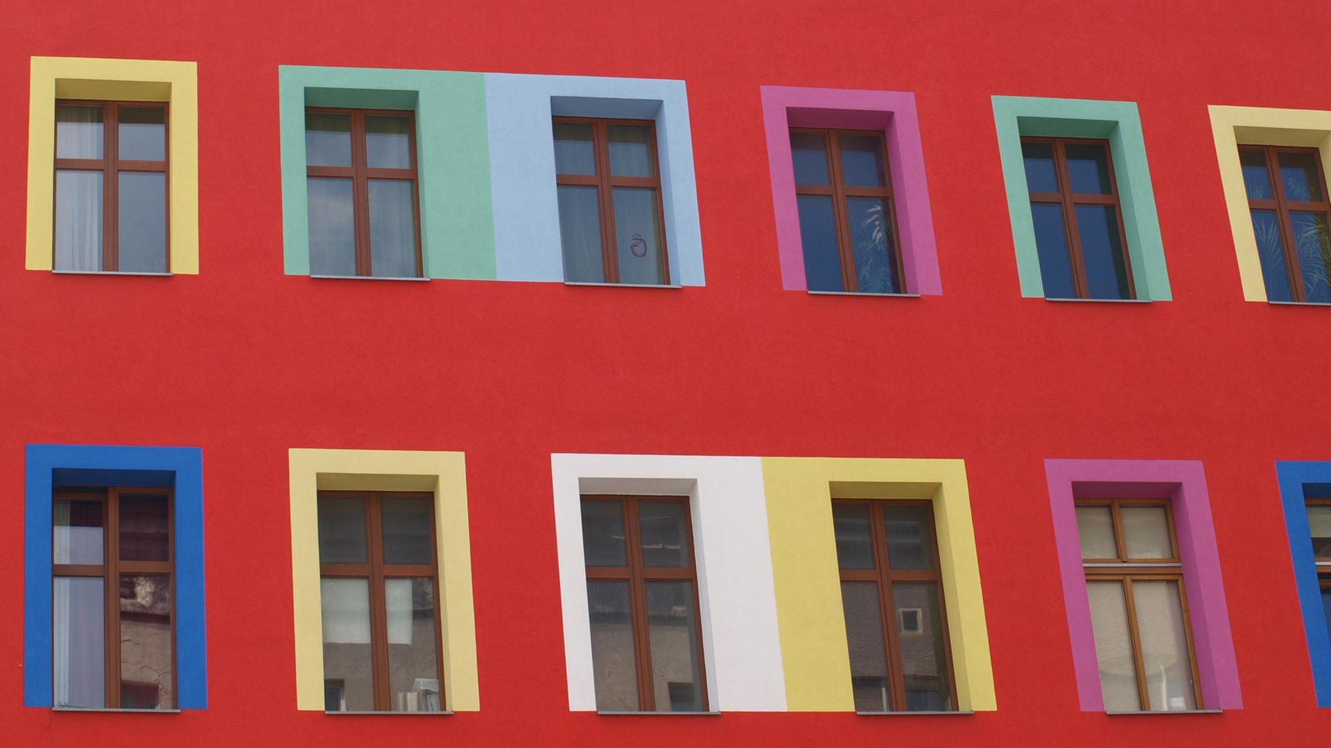 Blick auf die Fassade eines Mehrfamilienhauses mit bunten Fensterrahmen. Blick auf die Fassade eines Mehrfamilienhauses mit bunten Fensterrahmen.
