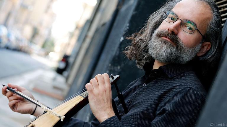 Der Lyraspieler sitzt auf einer Straße und spielt sein Instrument im Sitzen. Der Lyraspieler sitzt auf einer Straße und spielt sein Instrument im Sitzen.