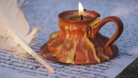 Ein Federkiel mit Papier und Kerze