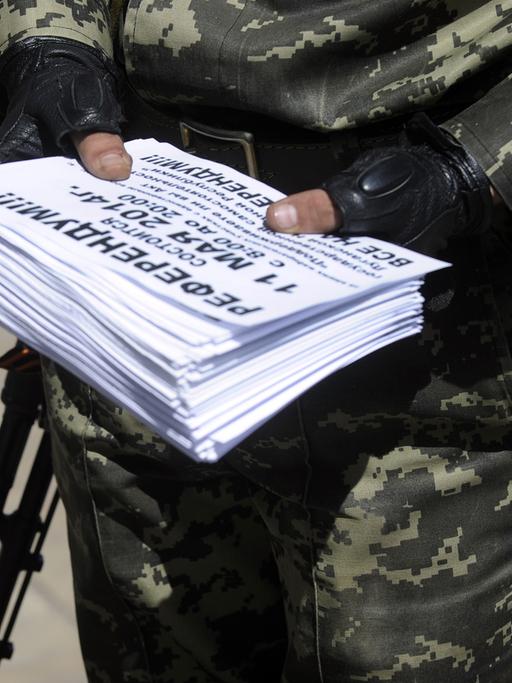 Ein Mitglied der sogenannten Volksarmee in der Ostukraine hält Einladungen zum Referendum über die Unabhängigkeit der Regionen Donezk und Lugansk in den Händen.