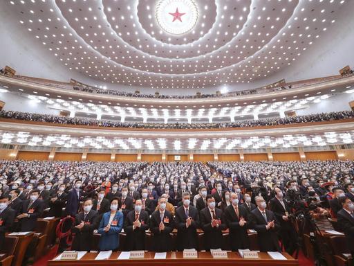 Beim 13. Nationale Volkskongress in China in Peking stehen die Teilnehmer auf und klatschen.