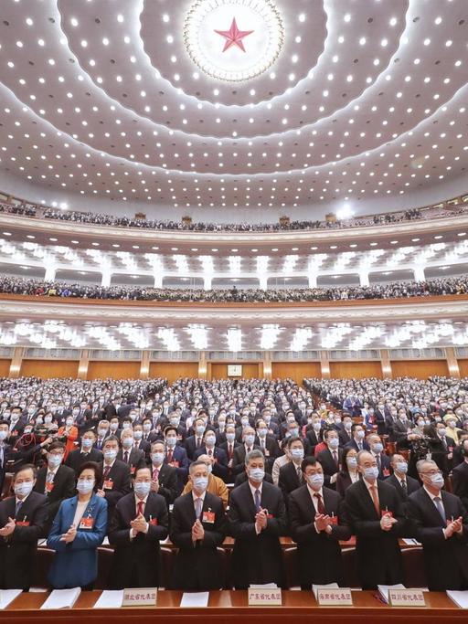 Beim 13. Nationale Volkskongress in China in Peking stehen die Teilnehmer auf und klatschen.