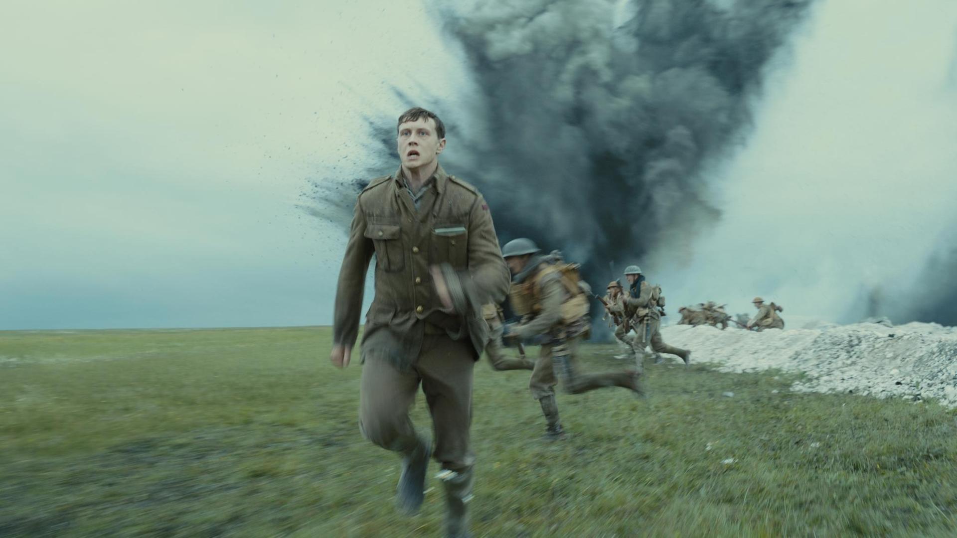 Eine Filmszene aus 1917 zeigt George MacKay als Soldat Schofield, der vor einer Explosion im Schützengraben davonläuft. Eine Filmszene aus 1917 zeigt George MacKay als Soldat Schofield, der vor einer Explosion im Schützengraben davonläuft.