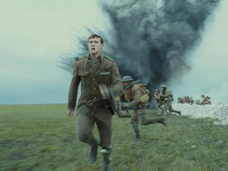 Eine Filmszene aus 1917 zeigt George MacKay als Soldat Schofield, der vor einer Explosion im Schützengraben davonläuft.