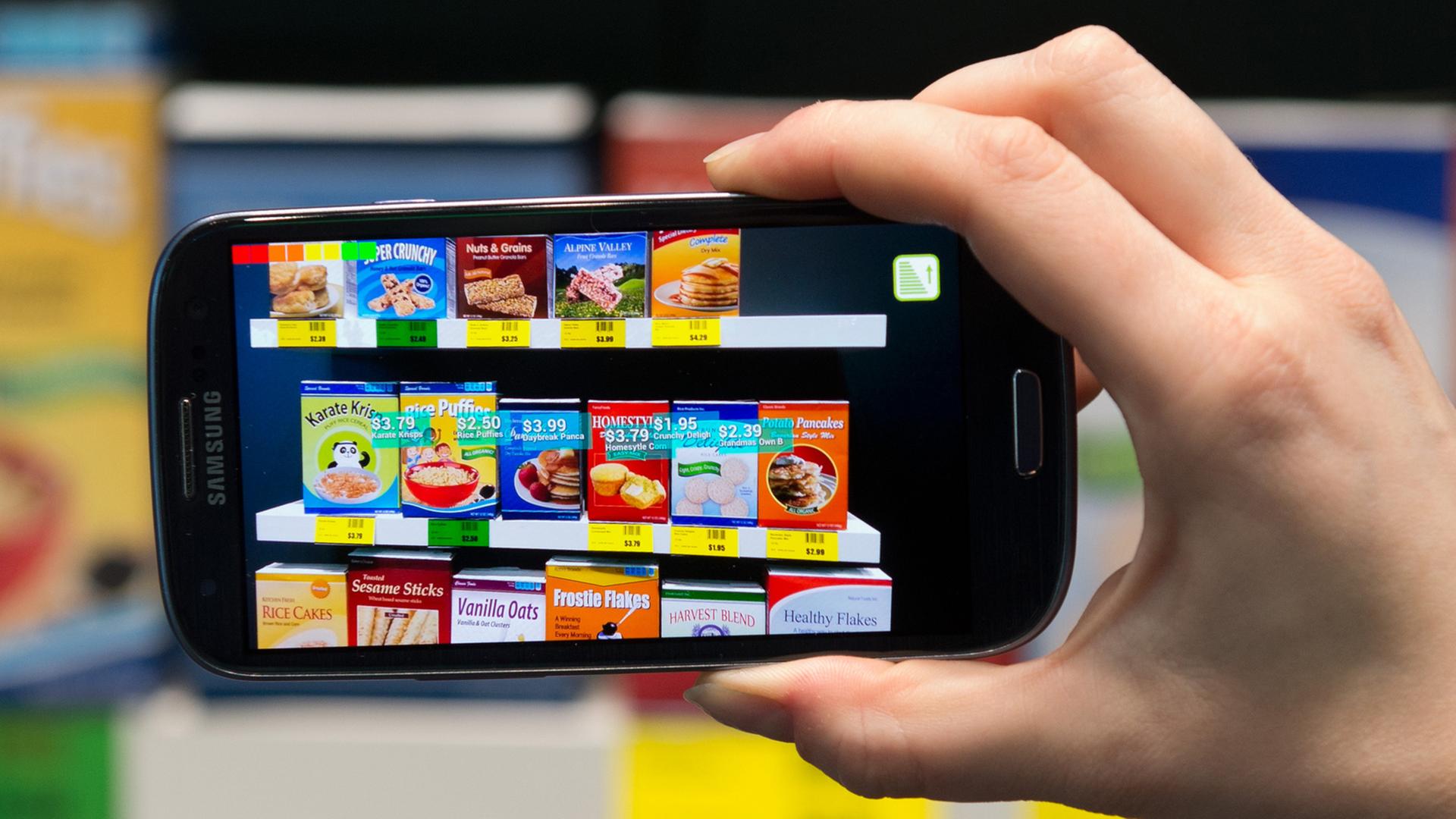 Eine Hand hält ein eingeschaltetes Smartphone, auf dem zahlreiche Apps installiert sind. Eine Hand hält ein eingeschaltetes Smartphone, auf dem zahlreiche Apps installiert sind.