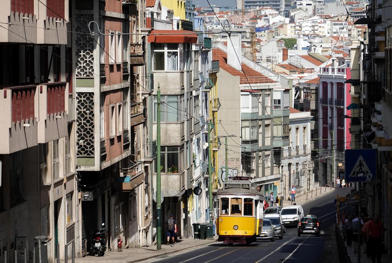Eine Straßenbahn der Linie 28 fährt einen Berg hoch durch ein Wohnviertel von Lissabon. Eine Straßenbahn der Linie 28 fährt einen Berg hoch durch ein Wohnviertel von Lissabon.
