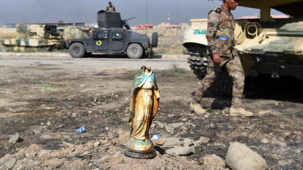 Ein irakischer Soldat läuft an einer zerbrochenen Statue der Jungfrau Maria vorbei. Mossul, Irak, 2016. Ein irakischer Soldat läuft an einer zerbrochenen Statue der Jungfrau Maria vorbei. Mossul, Irak, 2016.