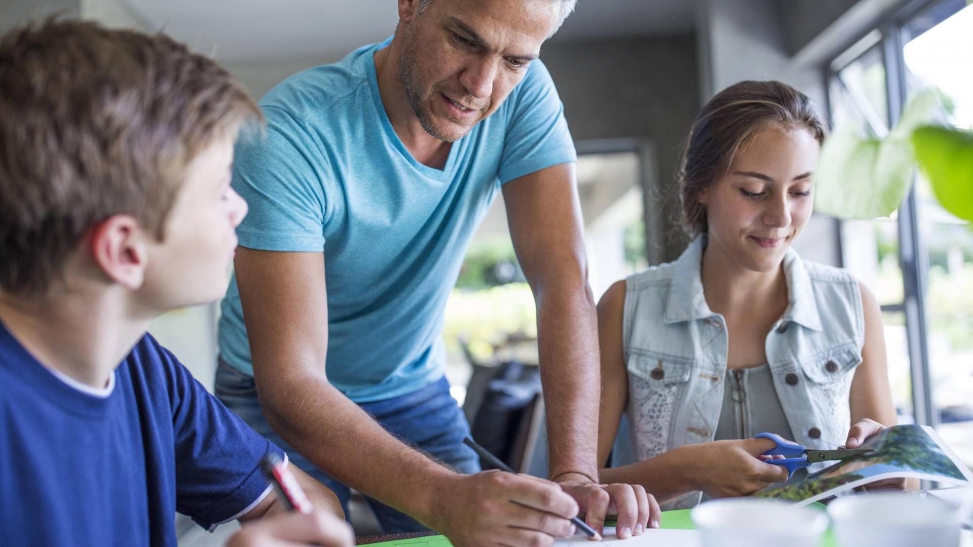 Ein Vater mit Tochter und Sohn bei den Hausaufgaben